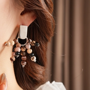 Close-up of ethnic style silver earring with natural brown and beige stone beads