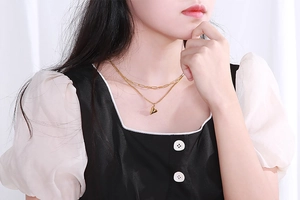 Collier double rang en titane doré avec pendentif cœur et chaîne à maillons carrés sur un modèle