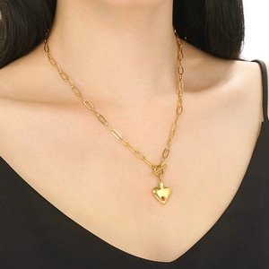 Detail of golden heart pendant necklace with T-bar toggle clasp worn by a model