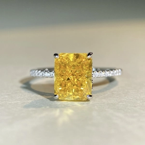 Macro shot of Radiant-cut yellow gemstone ring with pavé-set diamond band detail