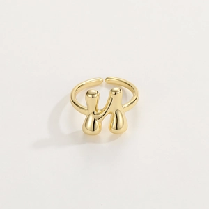 Macro shot of liquid metal style gold H-letter ring with polished finish and open design