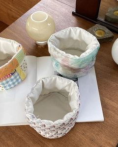 Detailed top view of three fabric storage baskets with floral and plaid patterns on wood