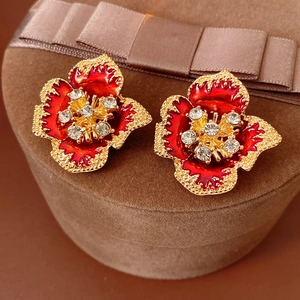 Macro shot of vintage red enamel flower earrings with sparkling crystal center on velvet