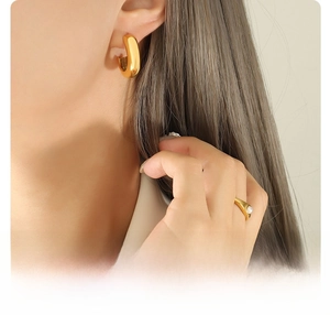 Gros plan sur une boucle d'oreille créole et bague perle en acier titane doré 18 carats