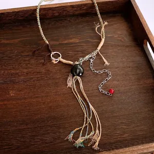 Collier ethnique en corde tressée avec gland en bois et anneau argenté sur plateau
