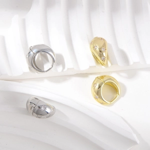 Detail of star-embossed hoop earrings in gold and silver finish with zircon stones