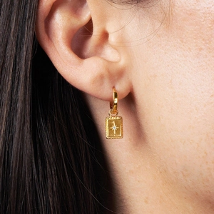 Macro detail of gold starburst rectangle pendant on hoop earrings with zircon