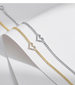 Detailed macro view of heart-shaped pendants in silver and gold with white zircon stones