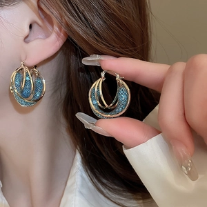 Detail of gold ear cuff featuring blue mesh texture on model for a trendy summer look