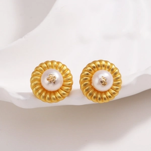 Gros plan de boucles d'oreilles fleur plaquées or 18 carats avec perle blanche