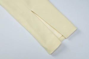 Detailed macro view of cream yellow woven fabric showing slit design on sleeve hem