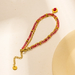 Close-up of double-layer stainless steel bracelet with pink beads and red stone pendant