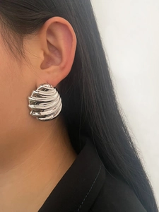 Close-up of a silver geometric wave textured earring worn by a model in a high-quality shot
