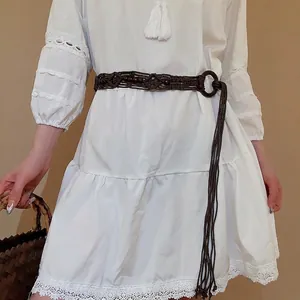 Bohemian woven waist chain with dark ring buckle on white lace dress with straw bag