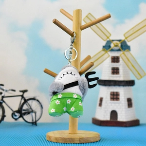 Funny shark plush keychain holding a pitchfork on a wooden stand display
