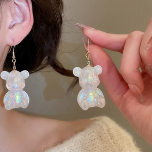 Close-up of sparkling colorful resin bear earrings with gold hooks on a female model