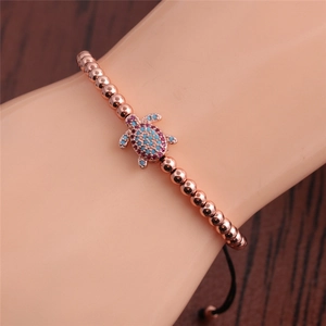 Detail of rose gold beaded bracelet featuring a colorful zircon turtle and adjustable cord