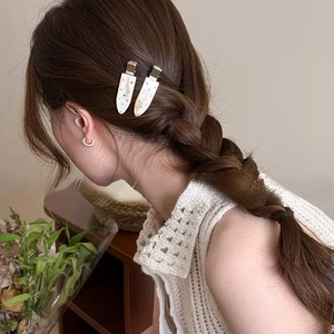 Detail of cream white teardrop hair clips with shimmering rhinestones on model side hair