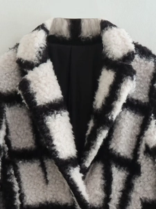 Close-up of fluffy black and white plaid faux fur coat showing thick plush texture details