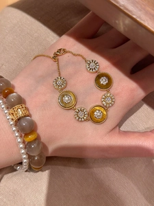 Détail du bracelet en or 18k avec pierre œil de tigre et motif de fleurs en zircon