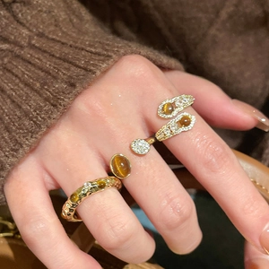 Macro shot of tiger eye and zircon rings set in vintage gold on model fingers