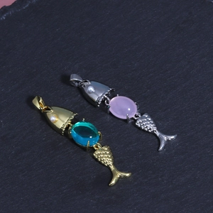 Macro detail of jointed 18K gold and silver fish pendants with gems and small pearls