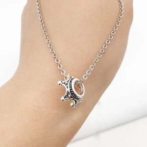 Detailed close-up of a vintage silver alloy crown pendant on a delicate metal chain