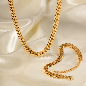 Ensemble collier et bracelet en maille gourmette dorée sur fond de soie blanche