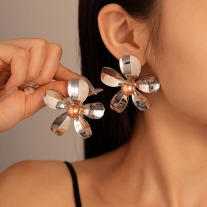 Silver metallic flower stud earrings with champagne pearl centers on model