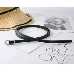 Chic black slim leather belt with silver oval buckle styled on a fashion magazine