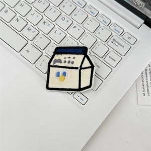 Close-up of a cartoon milk carton embroidery patch on a laptop keyboard background