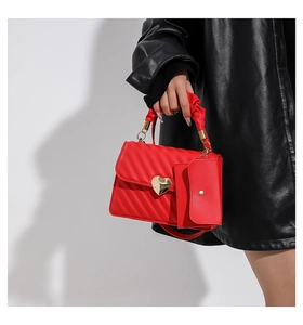 Detail of red quilted leather handbag with ruffled handle and gold heart clasp