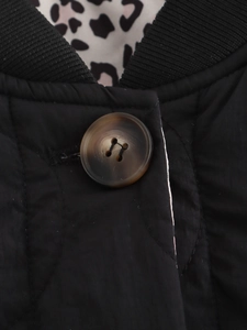 Detail of black quilted jacket with brown resin buttons and leopard print lining