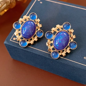 Detail of vintage gold earrings with deep blue gemstones on a jewelry box