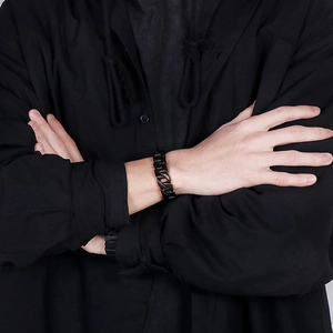 Gros plan d'un bracelet gourmette noire mate en acier inoxydable sur poignet homme