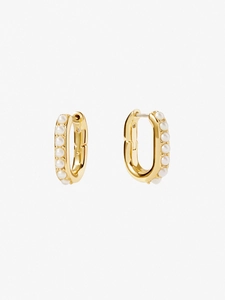 Close-up of gold U-shaped hoop earrings with row of white pearls on textured background