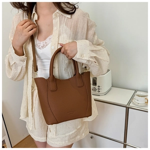 Détail d'un sac seau en cuir grainé caramel avec poignée et bandoulière réglable