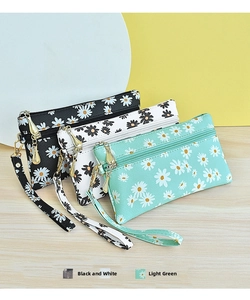 Detailed view of daisy print wristlet wallets in black, white and pale green faux leather