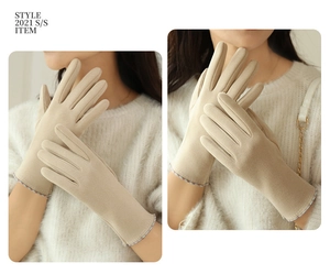 Detail of beige winter gloves with stylish plaid cuff and touch screen functionality