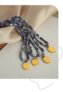 Detail of bohemian natural stone beaded necklace with engraved gold religious pendant