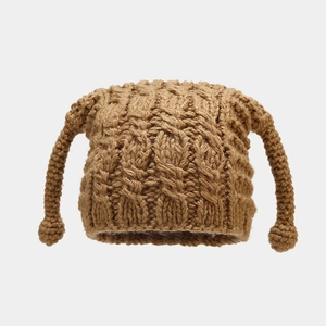 Macro shot of camel knit beanie with cable texture and whimsical decorative ear flaps