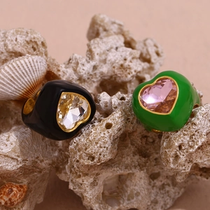 Macro detail of colorful heart gemstones on wide enamel rings set on a coral stone