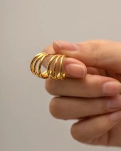 Detailed close-up of chunky gold-plated triple hoop earrings held by hand