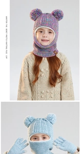 Close-up of knit winter balaclava with faux fur pom-poms and touchscreen gloves