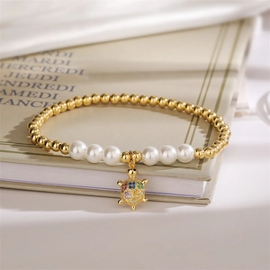 Detail of beaded pearl bracelet with gold beads and a colorful zircon turtle pendant