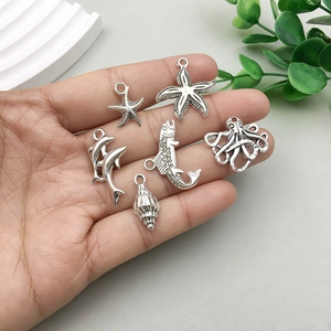Silver ocean series charms featuring starfish and dolphin pendants on a grey table