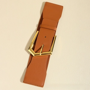 Detail of tan elastic wide waist belt for women with large golden hexagonal metal buckle