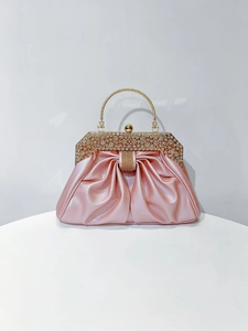 Detail of pink satin evening bag with rhinestone-encrusted gold handle and bow clasp