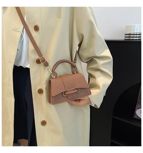 Détail du sac bandoulière marron texturé avec fermoir à nœud et poignée ronde