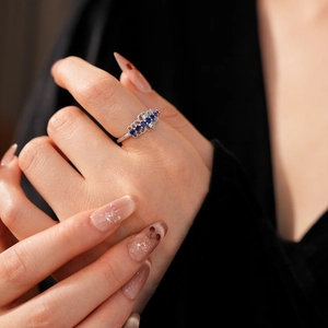Détail de bague en dentelle argentée avec cinq zircons bleu foncé et filigrane fin